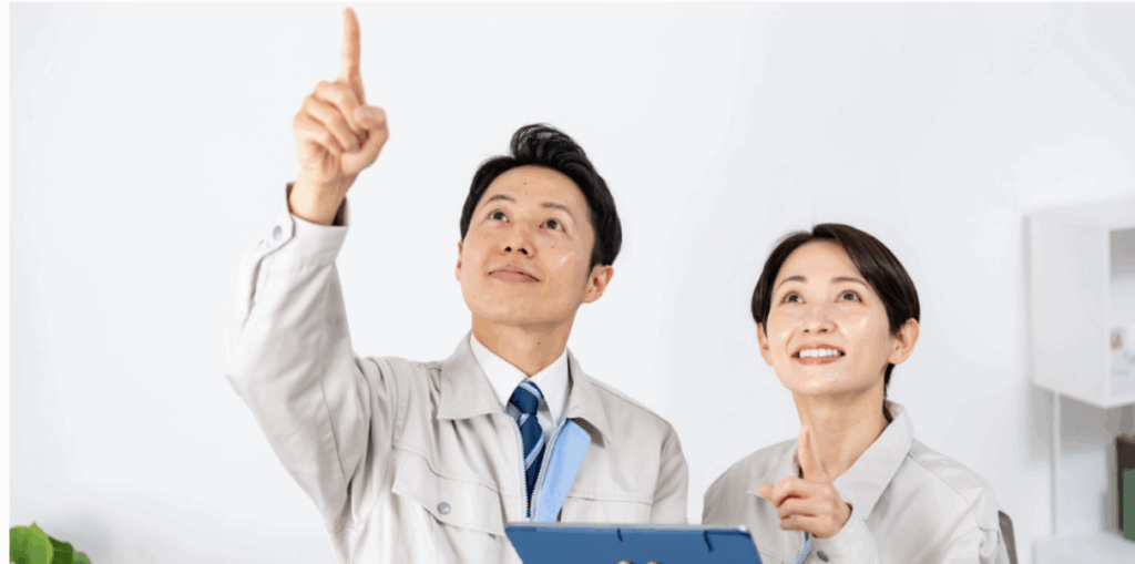 作業服を着た男女スタッフが天井方向を指差しながら家屋を点検している様子